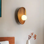 Oval vägglampa i trä med rund ljuskupa